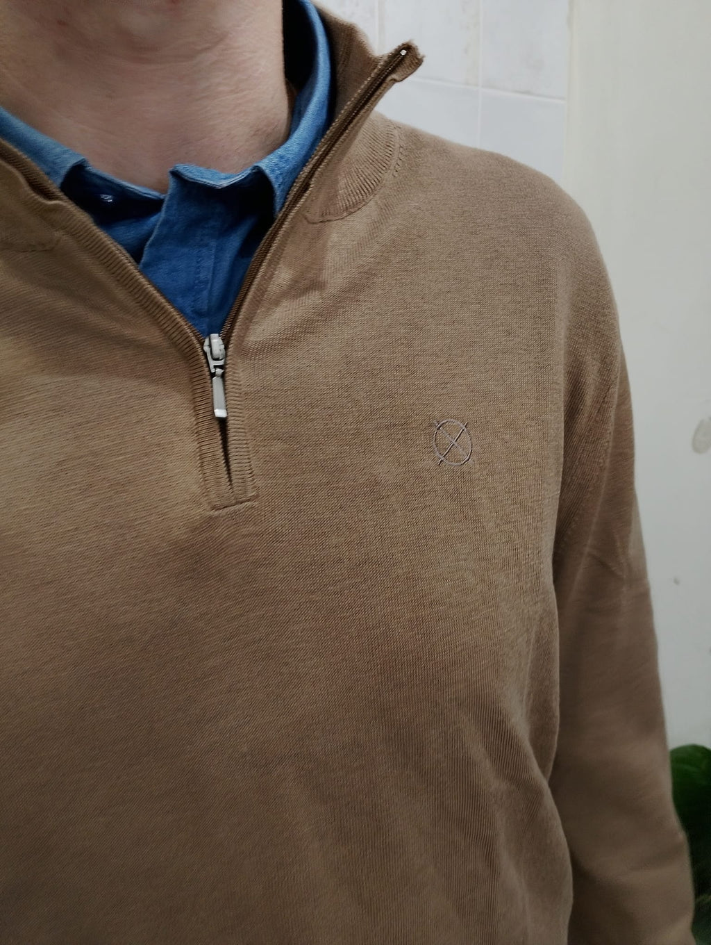 Detalle del cuello con media cremallera del jersey color tierra de ORIGEN STUDIO.