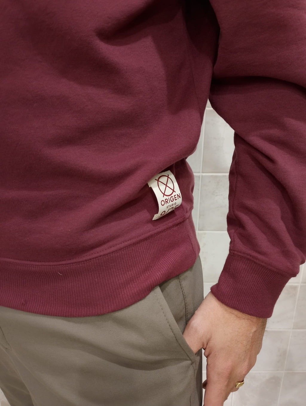Detalle lateral de la sudadera burdeos Origen Studio con etiqueta numerada edición limitada.