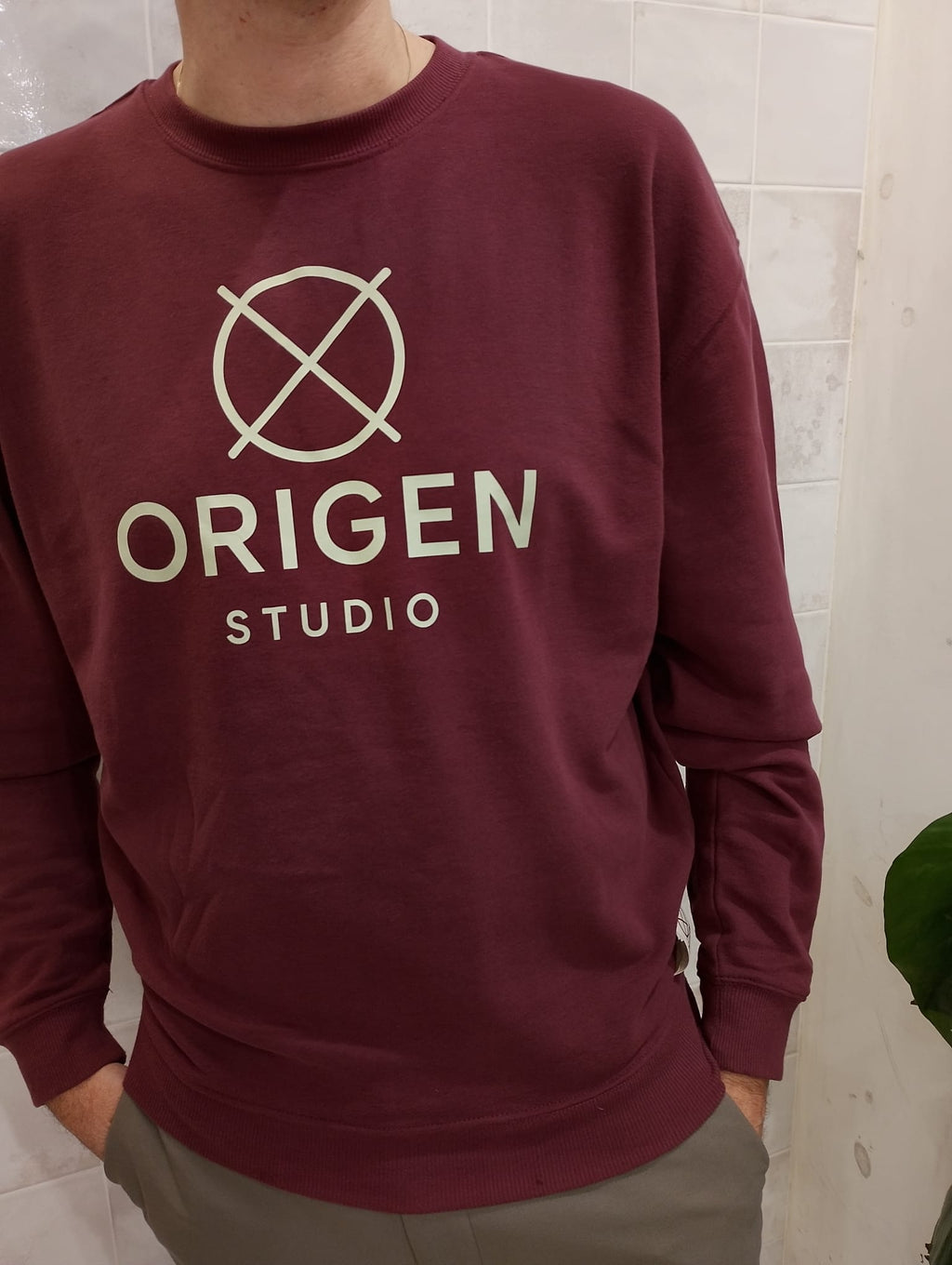 Sudadera burdeos Origen Studio con logo frontal impreso en color claro.