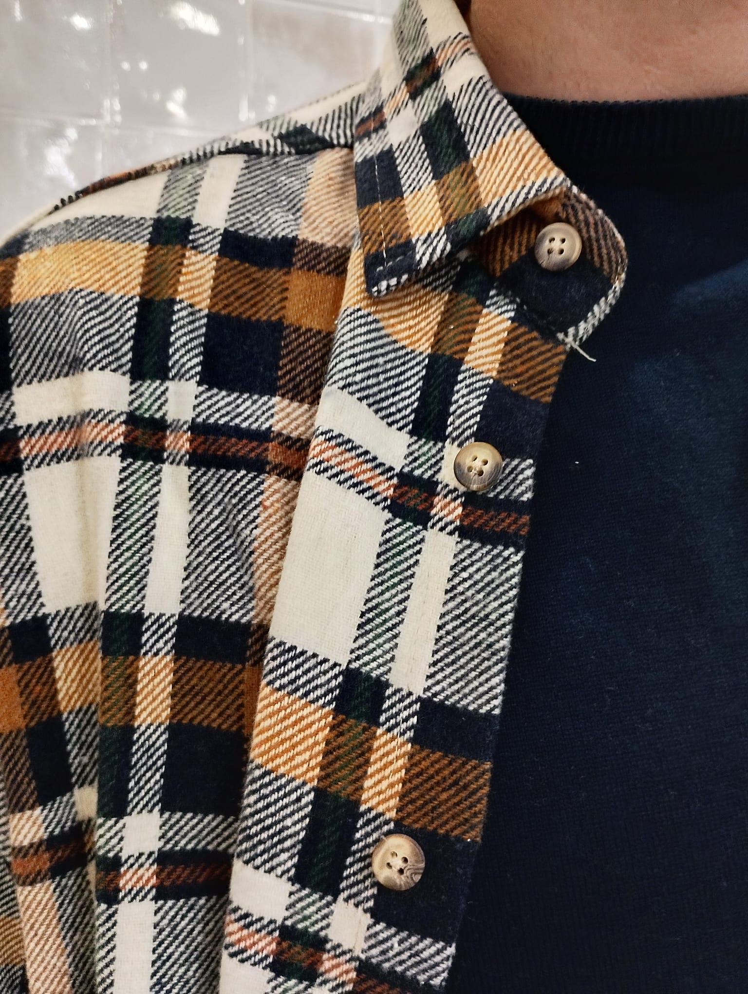 Detalle del cuello y tejido de la sobrecamisa de cuadros Origen Studio en tonos caramelo y navy