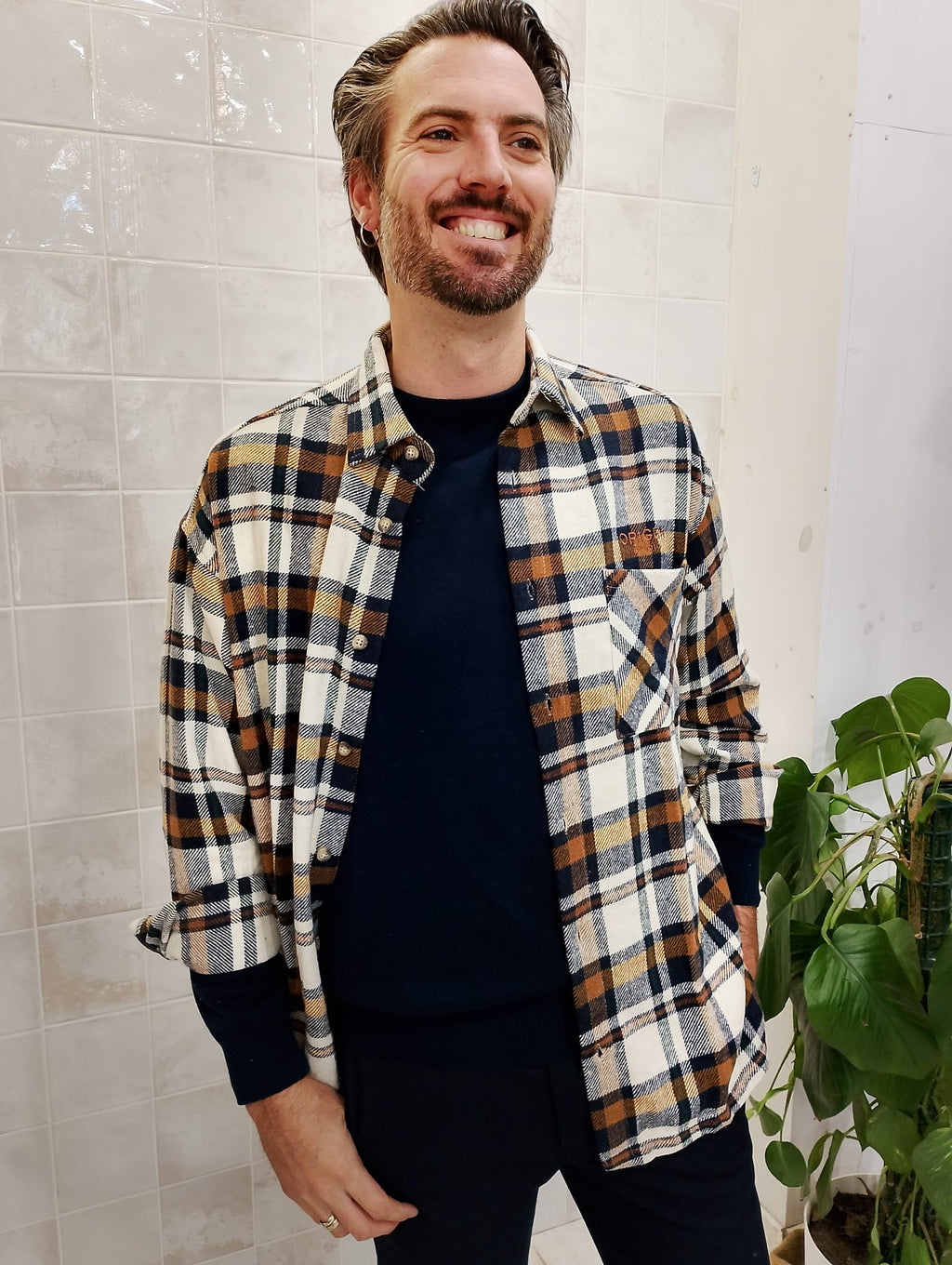 Hombre vistiendo la sobrecamisa Origen Studio de cuadros beige, caramelo y azul marino en look casual abierto