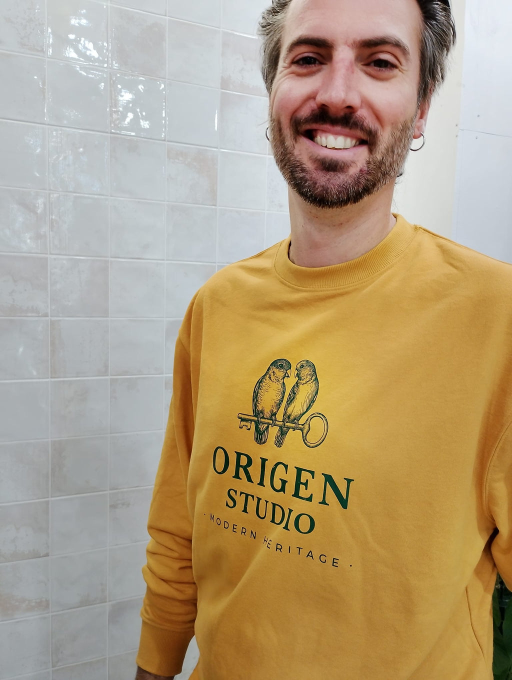 Sudadera Origen Studio color mostaza con diseño Heritage Birds, modelo sonriendo